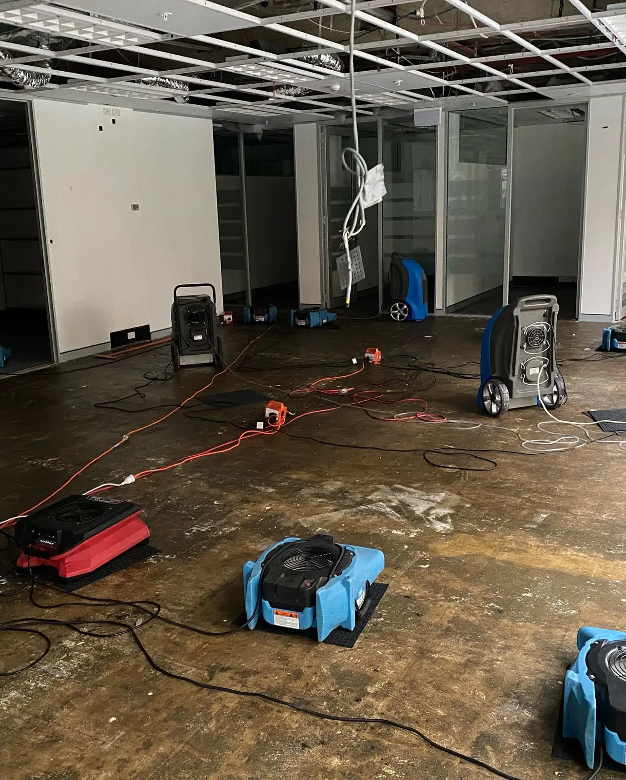Commercial water damage restoration with air movers and dehumidifiers operating on site